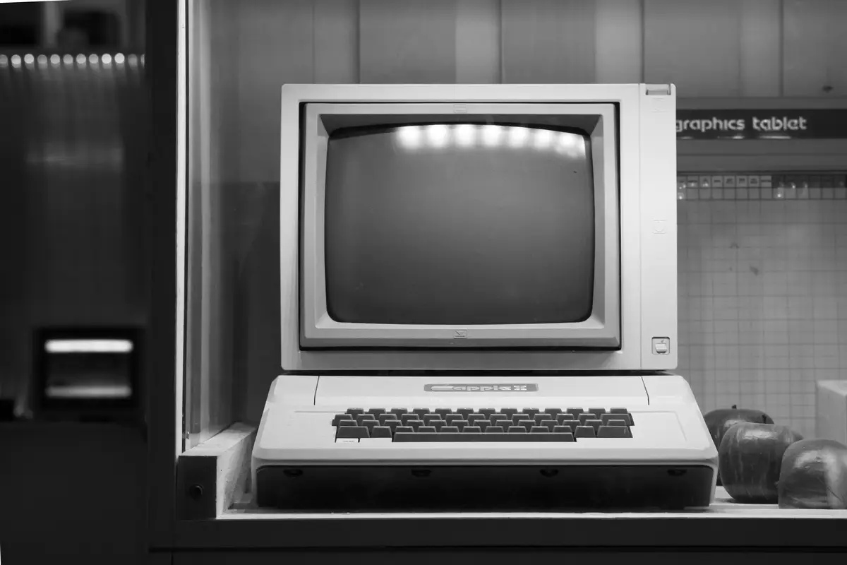Una computadora de escritorio antigua tras un cristal, en blanco y negro